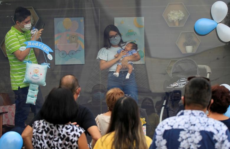 A couple is seen with their newborn baby inside a sanitized cabin called "Baby Cabin Parade" to show the newborn to relatives as a social distancing solution during the coronavirus outbreak in Monterrey, Mexico July 31. REUTERS/Daniel Becerril